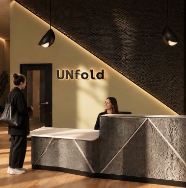 Unfold reception render with an angular perforated metal desk and warm lighting